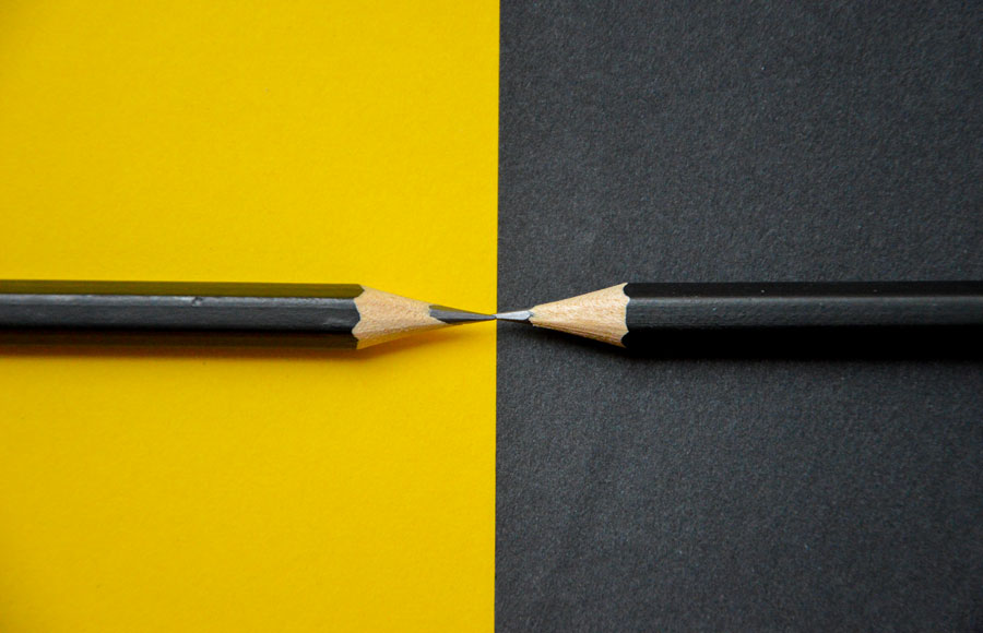 Two black pencils on black and yellow paper.