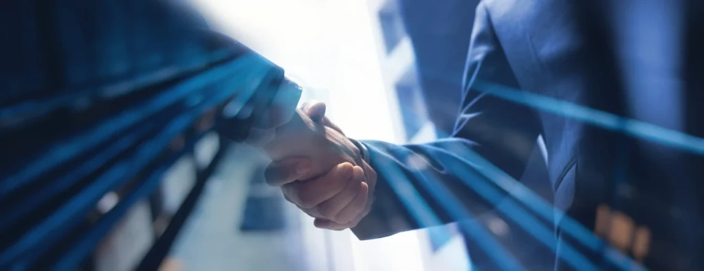 Two professionals in dark suits shake hands, overlaid by translucent beams of blue light intended to symbolize innovation and growth.