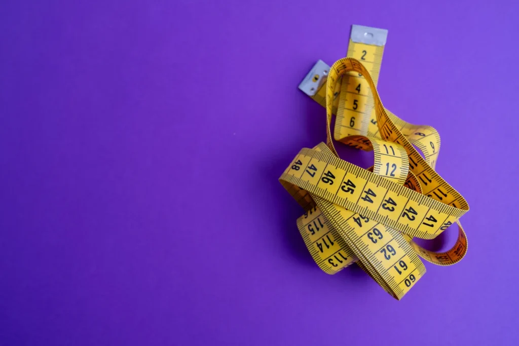 A deep purple backdrop supports a cloth, yellow measuring tape piled to the right of the photo.